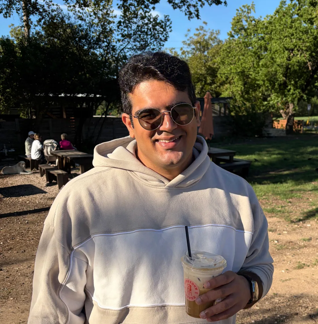 Samarth holding an iced coffee outdoors